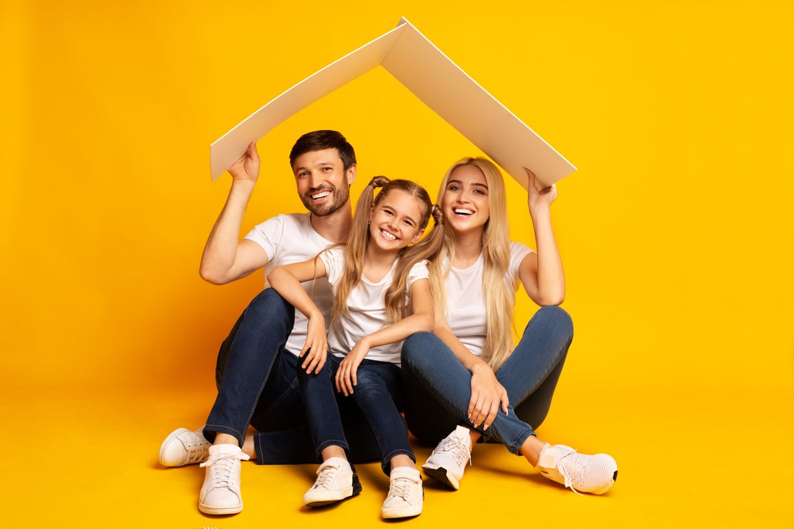 Family Housing. Parents And Daughter Sitting Under Roof, Studio Shot