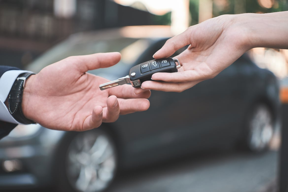 Car dealership.Young man receiving car key from saleswoman.