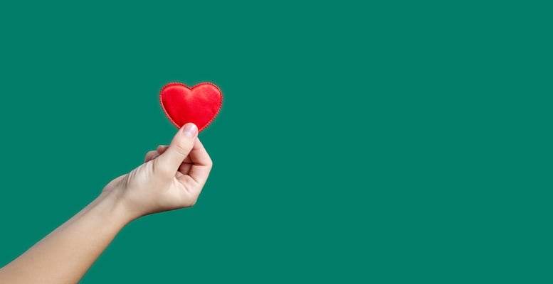 Hand holding red heart with copy space.Concept of Love and Health care,family insurance.World heart day, health day.Valentine's day. green background.